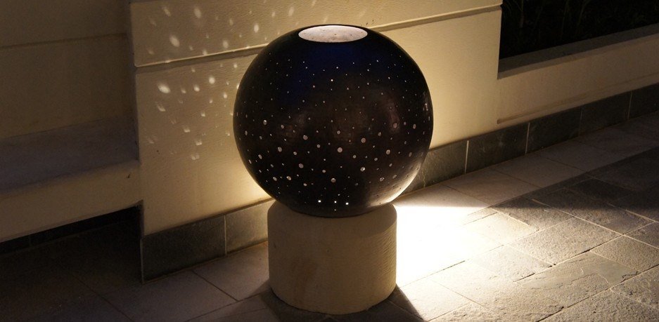 Pierced metal sphere lantern throwing points of light across a wall at Allure Waikiki