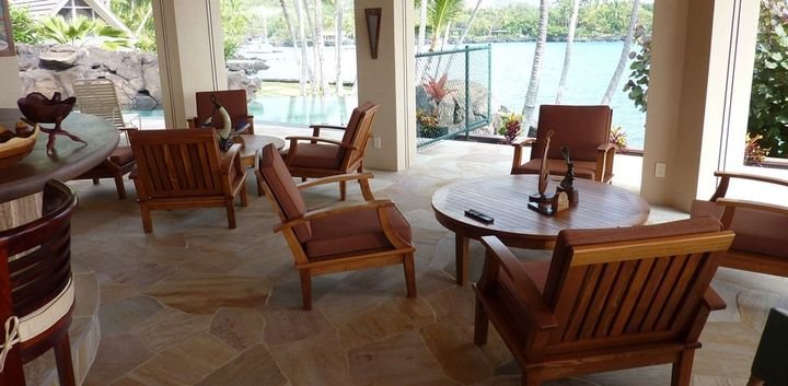 Open living room with teak armchairs and a low table facing the water, Keauhou Bay Residence, Hawaii Island