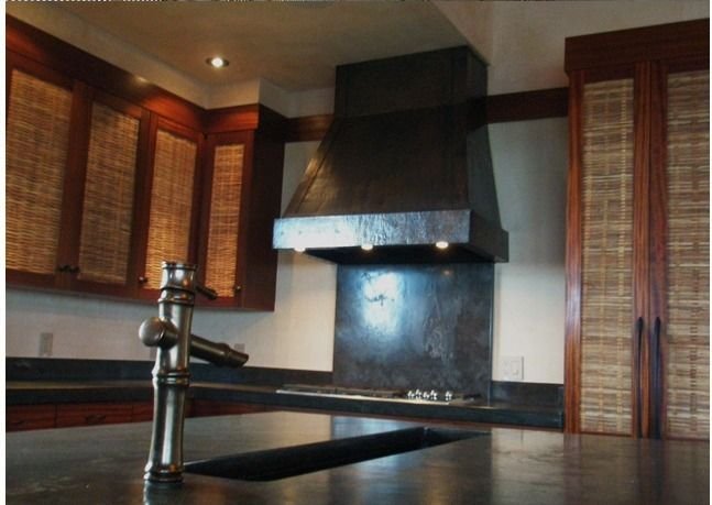 Kitchen interior with a dark metal range hood and timber shutters, Kukio Residence, Hawaii Island