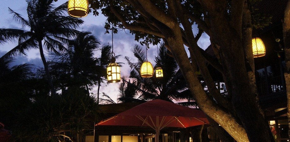 Pierced lanterns lit in the palms at dusk, Puri Santrian, Sanur, Bali